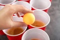 Woman holding yellow ball over cups arranged for playing beer pong, closeup Royalty Free Stock Photo