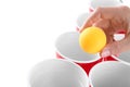 Woman holding yellow ball over cups arranged for playing beer pong, closeup Royalty Free Stock Photo