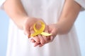 Woman holding yellow ribbon, closeup. Cancer awareness concept Royalty Free Stock Photo