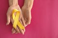 Woman holding yellow ribbon on color background. Cancer awareness concept Royalty Free Stock Photo