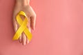 Woman holding yellow ribbon on color background. Cancer awareness concept Royalty Free Stock Photo