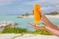 Woman holding yellow sunscreen bottle in hands