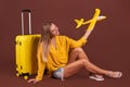 Woman holding yellow toy plane and suitcase. Air travel. planing summer trip in vacation