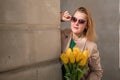 Woman holding yellow tulips, leaning against stone wall. Women& x27;s holiday concept, giving flowers. Royalty Free Stock Photo