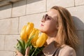 Woman holding yellow tulips, leaning against stone wall. Women& x27;s holiday concept, giving flowers. Royalty Free Stock Photo