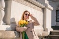 Woman holding yellow tulips, leaning against stone wall. Women& x27;s holiday concept, giving flowers. Royalty Free Stock Photo