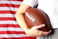 Woman holds American football ball on American flag background Royalty Free Stock Photo