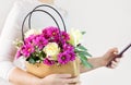 A woman holds a basket with flowers and a smartphone in her hands. Floristry, delivery from a flower shop Royalty Free Stock Photo