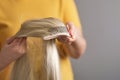 woman holds a blonde wig in her hands. Womens beauty concept. Closeup female customer selecting chignon of natural hair Royalty Free Stock Photo