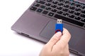 A woman holds a blue USB flash drive in her hand. Silver laptop with black keyboard on blurred background.  Isolated on white Royalty Free Stock Photo