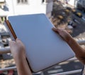 Woman holds with both hands a paper notebook and upper a laptop Royalty Free Stock Photo