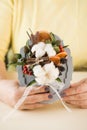 Woman holds bouquet with cotton flowers cinnamon and orange slices above table Royalty Free Stock Photo