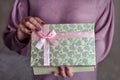 A woman holds a box with a pink ribbon with a gift