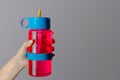 Woman holds bright pink eco water bottle in her hand for playing sports, on a gray background. Healthy lifestyle, yoga and fitness Royalty Free Stock Photo