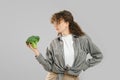 Woman holds broccoli in hand and looking at it
