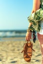 Woman holds brown leather sandals in her hand and looks at the sea Royalty Free Stock Photo