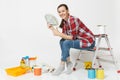 Woman holds bundle of dollars, cash money, sits on ladder with instruments for renovation apartment isolated on white Royalty Free Stock Photo