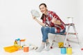 Woman holds bundle of dollars, cash money, sits on ladder with instruments for renovation apartment isolated on white Royalty Free Stock Photo