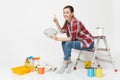 Woman holds bundle of dollars, cash money, sits on ladder with instruments for renovation apartment isolated on white Royalty Free Stock Photo