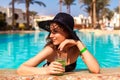 Woman holds a cocktail in hotel swimming pool. Summer vacation. All inclusive Royalty Free Stock Photo