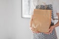 Woman holds craft eco shopping bag in hands, take away. Delivery food, mock up