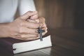 The woman holds the cross and prayes with her scriptures on the table