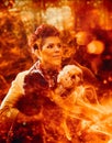 A woman holds a dog in front of a blazing fire, channeling the essence of an fire sorceress in a mystical forest.