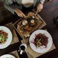 Woman holds a fork and knife in her hands and eats a beef steak with grilled eggplants and a vegetable salad with poached egg Royalty Free Stock Photo