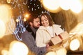 Woman holds gift box. Happy young couple celebrating New year outdoors on the street Royalty Free Stock Photo