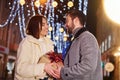 Woman holds gift box. Happy young couple celebrating New year outdoors on the street Royalty Free Stock Photo