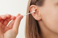 woman holds in hand disposable cotton bud, swab, stick. Girl cleans, washes her auricle earwax. Personal hygiene and
