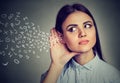 Woman holds hand near ear and listens carefully alphabet letters flying in