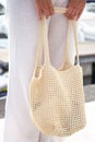 Woman holds a handmade beige knitted bag in her hand near her legs outdoors. Sustainable shopping. Wasteless lifestyle Royalty Free Stock Photo