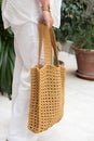 Woman holds a handmade beige knitted bag in her hand near her legs outdoors. Sustainable shopping. Wasteless lifestyle Royalty Free Stock Photo