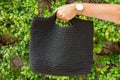 Woman holds a handmade black knitted bag in her hand near her legs outdoors. Sustainable shopping. Wasteless lifestyle Royalty Free Stock Photo