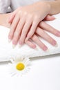 Woman holds hands on towel for manicure treatment procedure in spa salon. Beautiful hands of young woman close-up on towel. Royalty Free Stock Photo