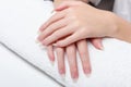 Woman holds hands on towel for manicure treatment procedure in spa salon. Beautiful hands of young woman close-up on towel. Royalty Free Stock Photo