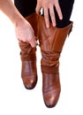 Woman holds her brown leather boots while zipping them up Royalty Free Stock Photo