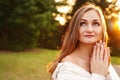 Woman holds her hands in prayer and looks up. Beautiful girl outdoors. Concept of faith in god