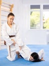 Sportive woman holds her opponent by force while sitting on mats during judo classes