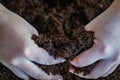 Woman holds with her two hands a handful of wet soil