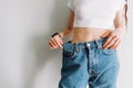 Woman holds jeans in hand, shows a thin waist Slim female body in large jeans Royalty Free Stock Photo