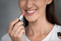 Close up cropped image woman holds lipstick near lips