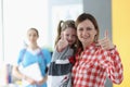 Woman holds little girl in her arms and they show thumbs up gesture on background is doctor