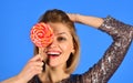 Woman holds lollipop hiding eye on blue background. Royalty Free Stock Photo