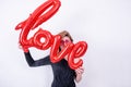 Woman holds love word shaped red balloon