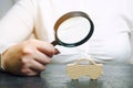 A woman holds a magnifying glass over a miniature wooden car. The estimated cost of the auto. Analysis and technical inspection of Royalty Free Stock Photo