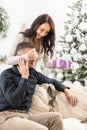 Woman holds man& x27;s eyes closed while she prepares a surprise Christmas present for him Royalty Free Stock Photo