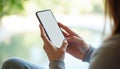 Woman holds modern smartphone with blank screen, scrolling content outdoors. Closeup of hand using mobile device for browsing or Royalty Free Stock Photo