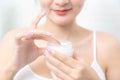 A woman holds a moisturizer in her hand and her skin and wrinkle from impurities